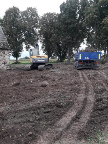 Koparka i samochód ciężarowy z prawej strony stodoły